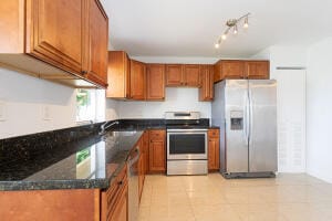 kitchen with appliances with stainless steel finishes, dark stone countertops, and light tile patterned flooring