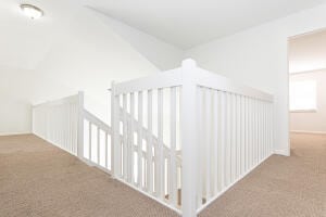 hallway with light carpet and vaulted ceiling