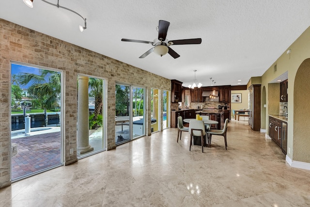 unfurnished dining area with a textured ceiling and ceiling fan with notable chandelier