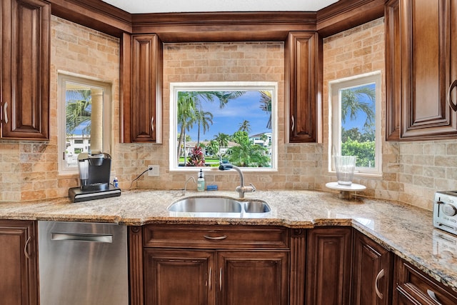 kitchen with stainless steel dishwasher, light stone counters, and sink