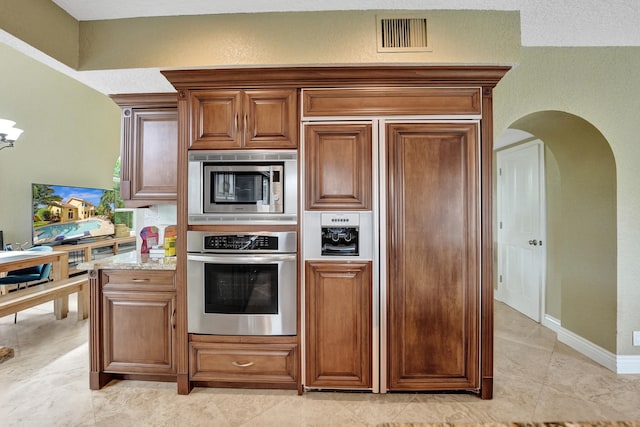 kitchen with built in appliances, light stone counters, and light tile patterned floors