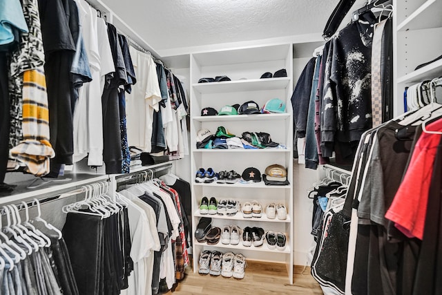 walk in closet with light hardwood / wood-style flooring