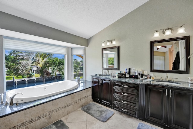 bathroom featuring tile patterned floors, vaulted ceiling, vanity, tiled bath, and a textured ceiling