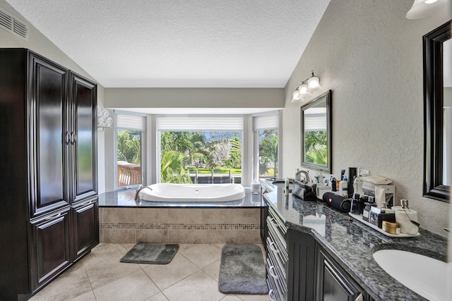 bathroom featuring vanity, a textured ceiling, tile patterned floors, and tiled bath