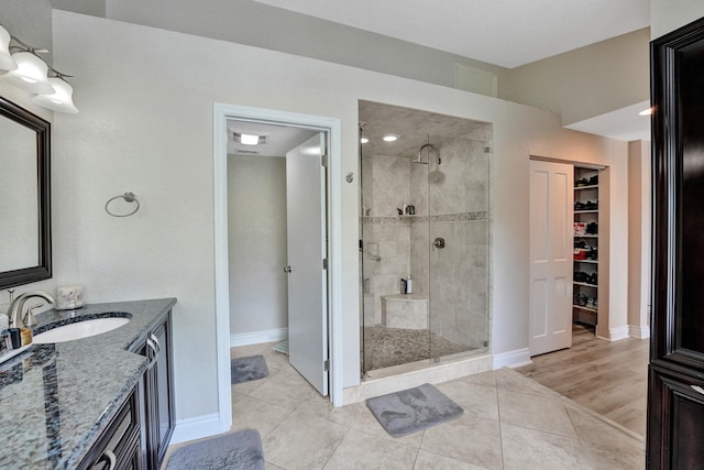 bathroom featuring hardwood / wood-style floors, a shower with door, and vanity