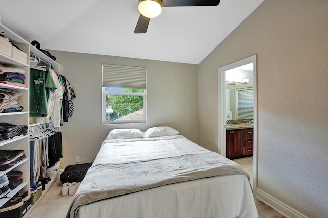 bedroom featuring ceiling fan, ensuite bathroom, and vaulted ceiling