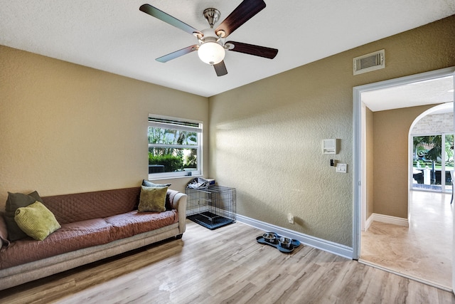 living room with a textured ceiling, light hardwood / wood-style flooring, and ceiling fan