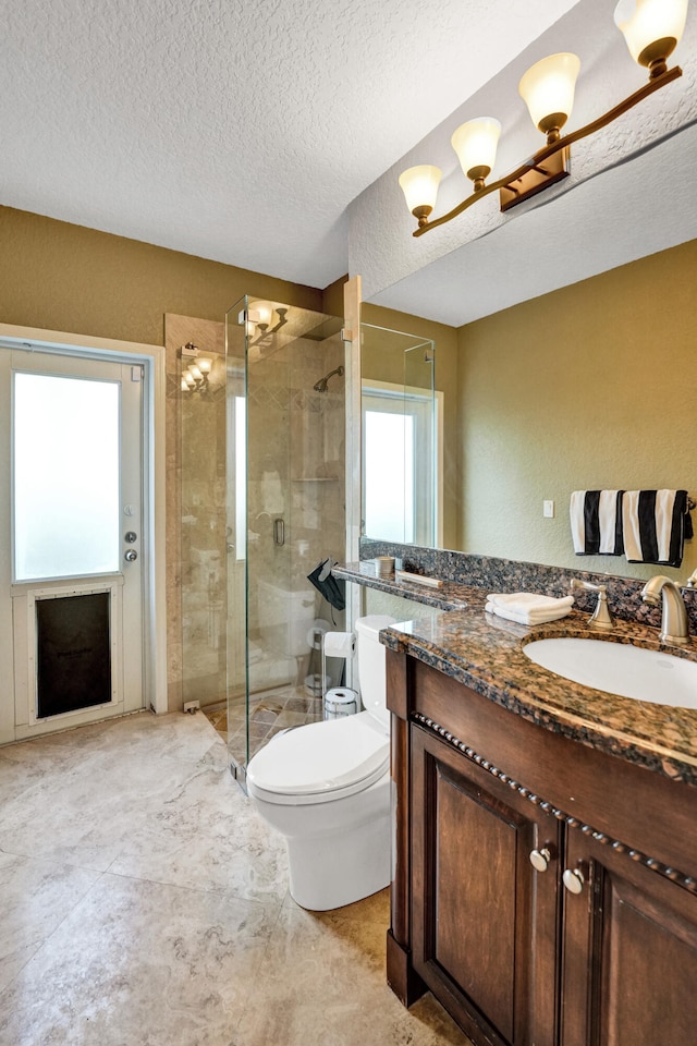 bathroom featuring a textured ceiling, vanity, toilet, and walk in shower