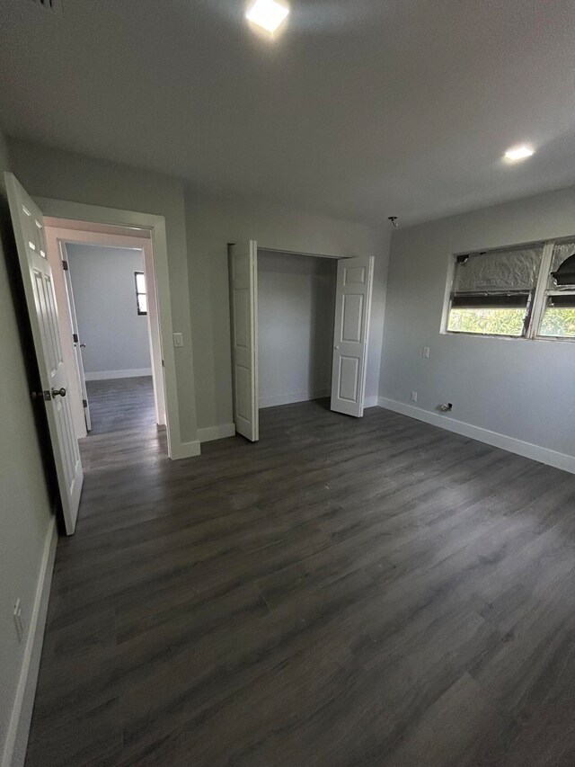 unfurnished bedroom with dark wood-type flooring and a closet