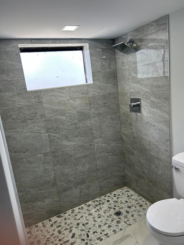 bathroom with toilet and a tile shower