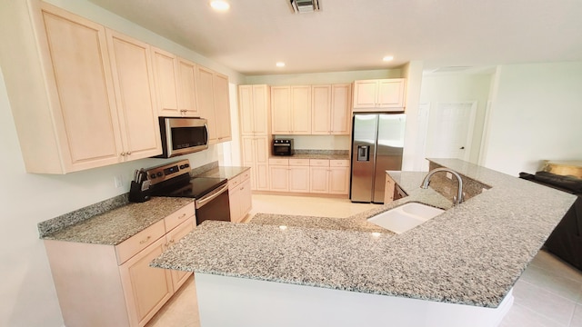 kitchen featuring light tile patterned flooring, sink, stainless steel appliances, a center island with sink, and light stone countertops