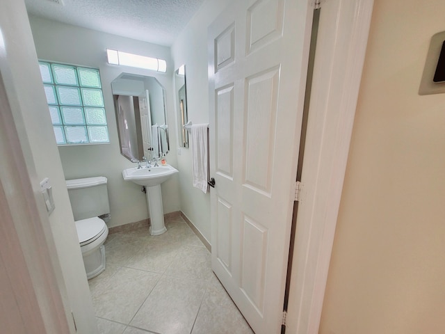 bathroom with a textured ceiling, tile patterned flooring, and toilet