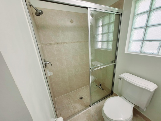 bathroom featuring a shower with door and toilet