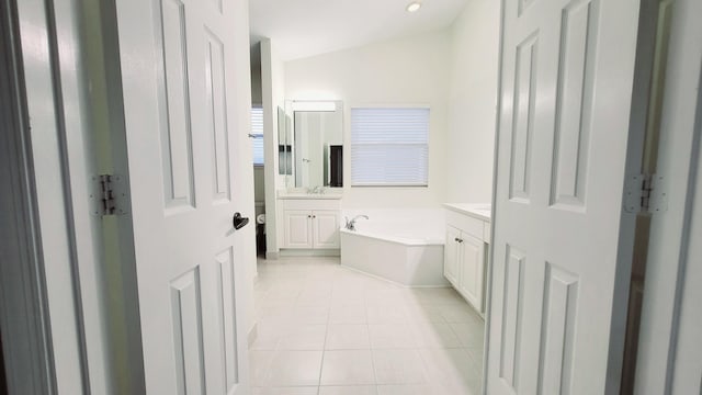 bathroom featuring vanity, a bathing tub, lofted ceiling, and tile patterned floors