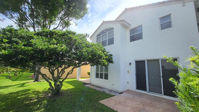 rear view of property featuring a yard and a patio area