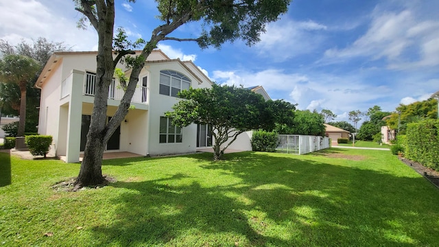 rear view of house with a lawn and a balcony