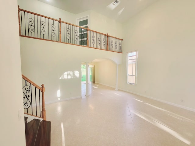 unfurnished living room with a high ceiling, tile patterned flooring, and ornate columns