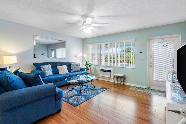 living room featuring a wall mounted air conditioner, a textured ceiling, hardwood / wood-style flooring, and ceiling fan