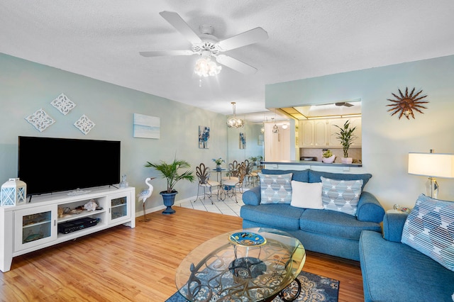 living room with a textured ceiling, ceiling fan, and light hardwood / wood-style floors