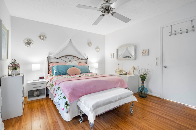 bedroom with a textured ceiling, ceiling fan, and light hardwood / wood-style floors