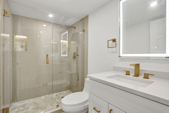 bathroom featuring vanity, a shower with door, and toilet