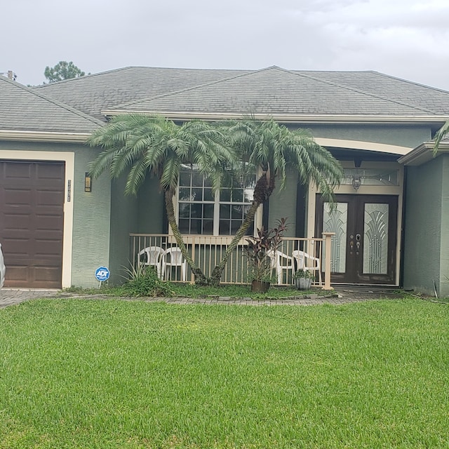 view of exterior entry featuring a yard, stucco siding, a garage, and french doors