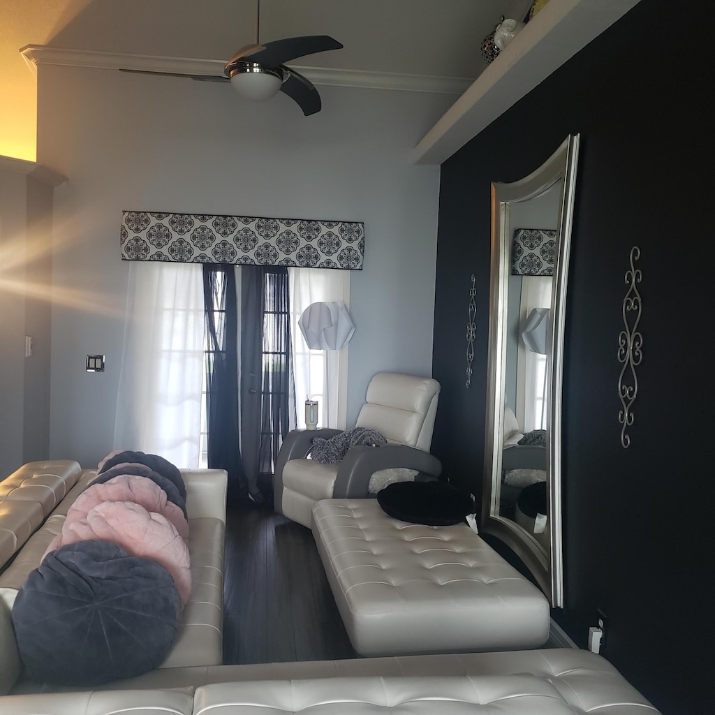 living area with a ceiling fan, wood finished floors, and crown molding