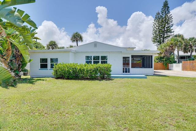 back of property featuring a sunroom and a lawn