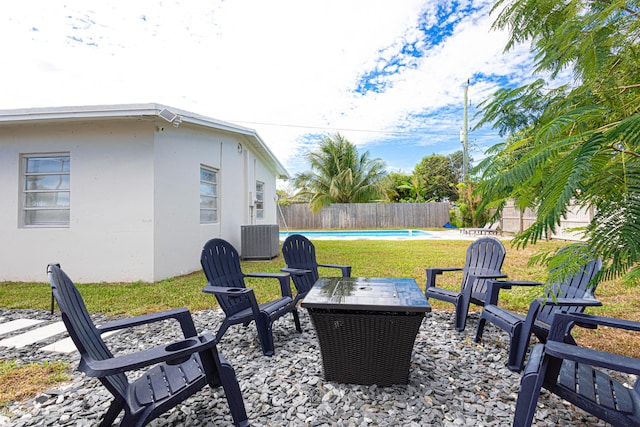 view of patio featuring a fenced in pool, a fire pit, and central AC