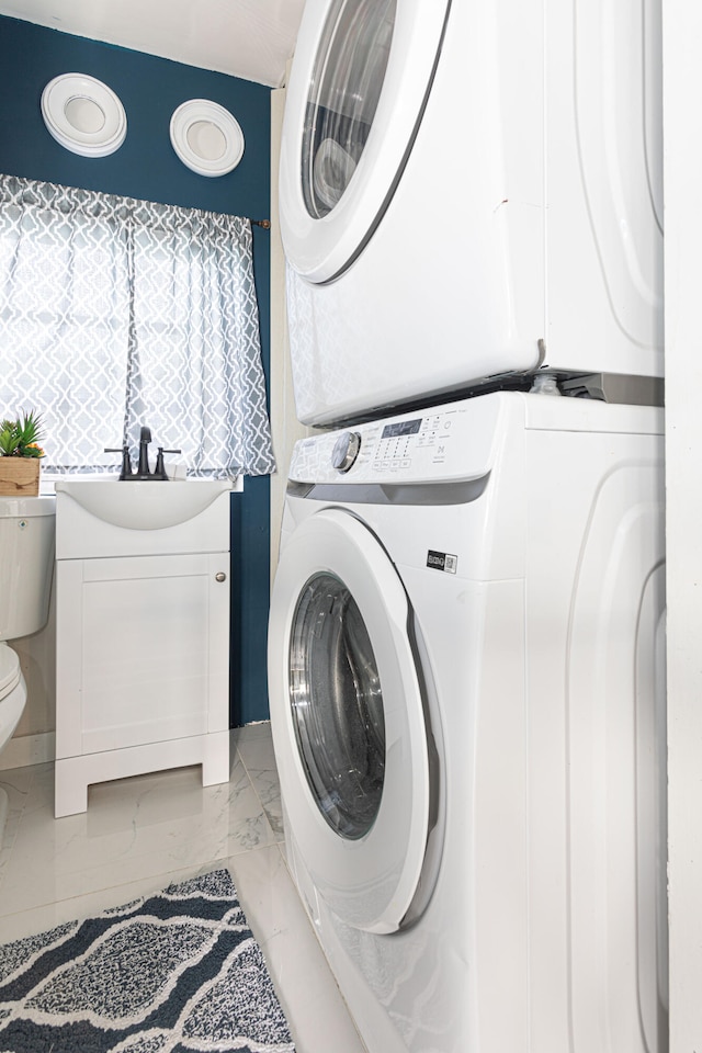 laundry area featuring stacked washer / drying machine and sink