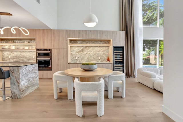 dining area featuring plenty of natural light, a towering ceiling, and light hardwood / wood-style flooring