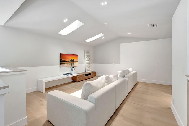 living room with vaulted ceiling with skylight and light hardwood / wood-style floors