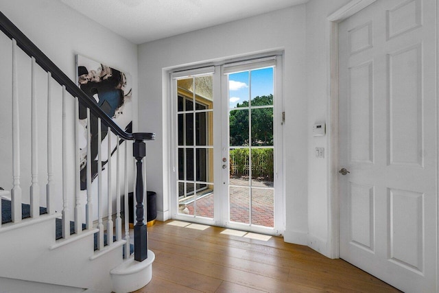 entrance foyer with a textured ceiling, a wealth of natural light, and wood-type flooring