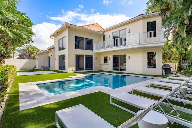 back of house with a lawn, a patio area, and a balcony