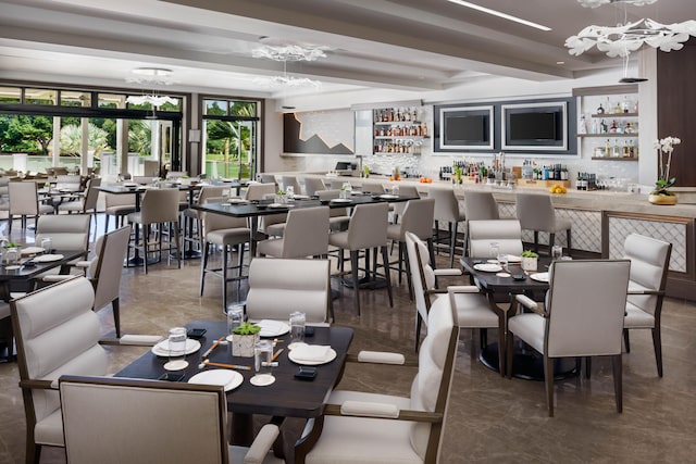 dining space featuring bar, a chandelier, and beam ceiling