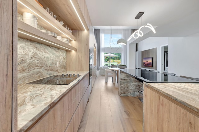 kitchen featuring decorative light fixtures, light brown cabinetry, light hardwood / wood-style floors, and black electric cooktop