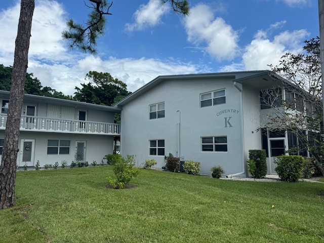 rear view of house with a balcony and a yard