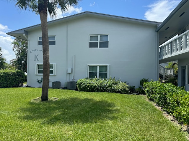 rear view of property featuring cooling unit, a balcony, and a lawn