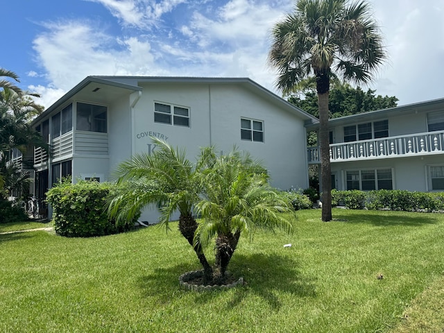 view of home's exterior featuring a balcony and a lawn