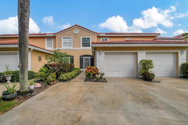 view of front of house featuring concrete driveway, a tiled roof, and stucco siding