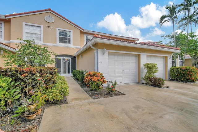 view of front of property with a garage, a tile roof, concrete driveway, and stucco siding