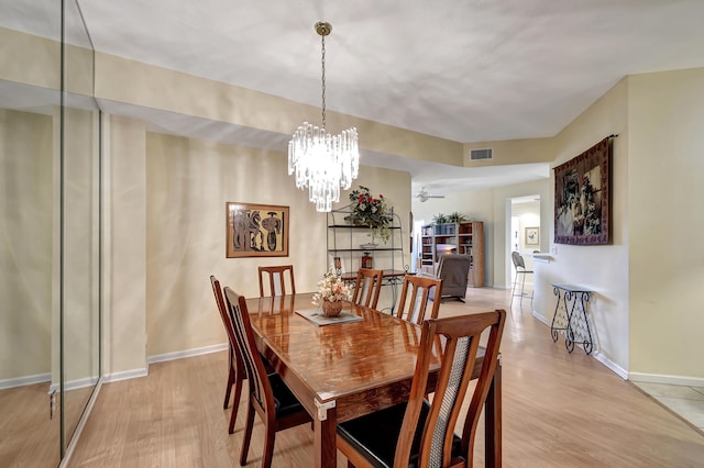 dining space featuring ceiling fan with notable chandelier and light hardwood / wood-style floors