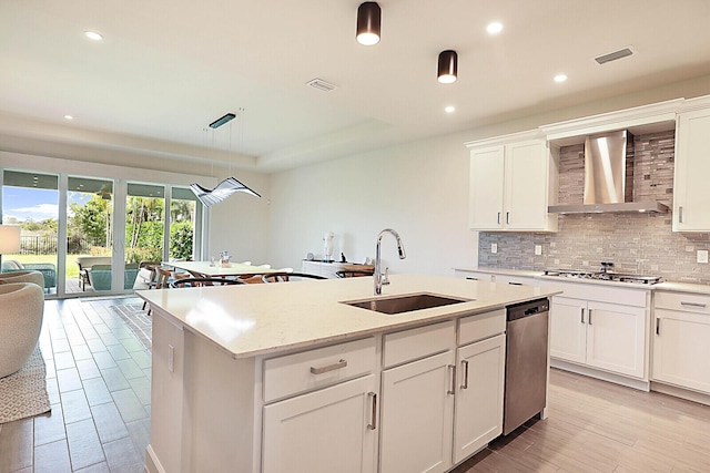 kitchen featuring pendant lighting, sink, white cabinetry, appliances with stainless steel finishes, and wall chimney exhaust hood