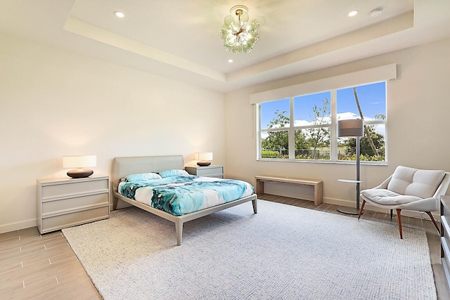 bedroom with a tray ceiling and light hardwood / wood-style flooring