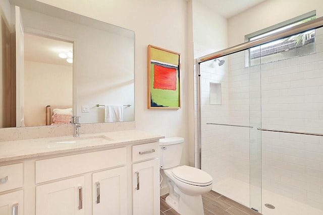 bathroom featuring toilet, walk in shower, and vanity