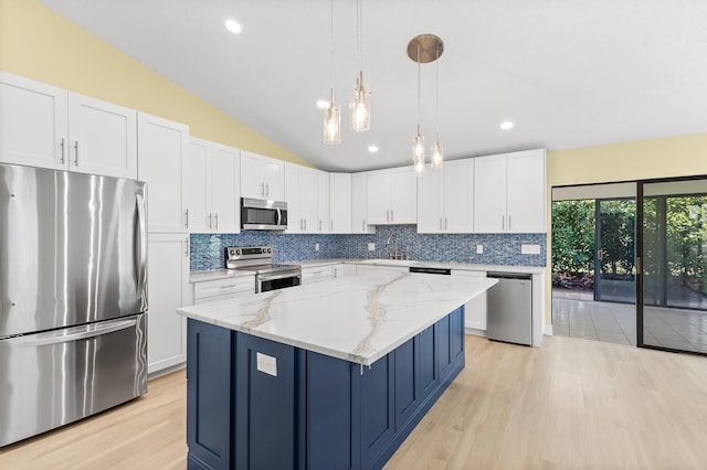 kitchen with lofted ceiling, a kitchen island, appliances with stainless steel finishes, and decorative backsplash