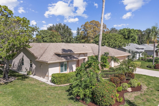 single story home featuring driveway, a front lawn, an attached garage, and stucco siding