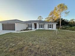 view of front of house featuring an attached garage, driveway, and a front lawn