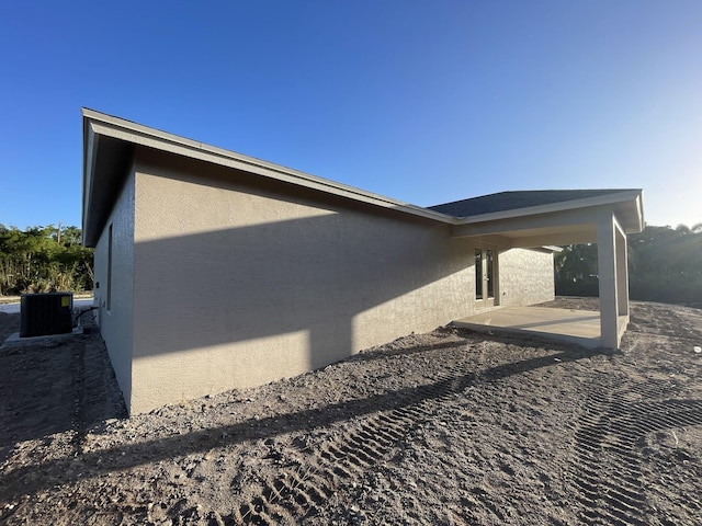 view of side of property with central AC unit and a patio