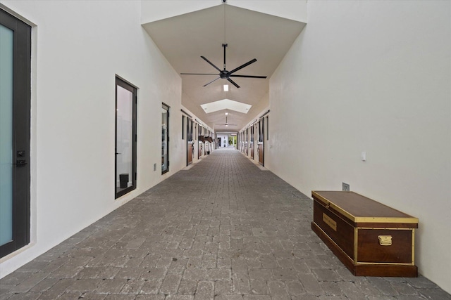 hallway with high vaulted ceiling and a skylight